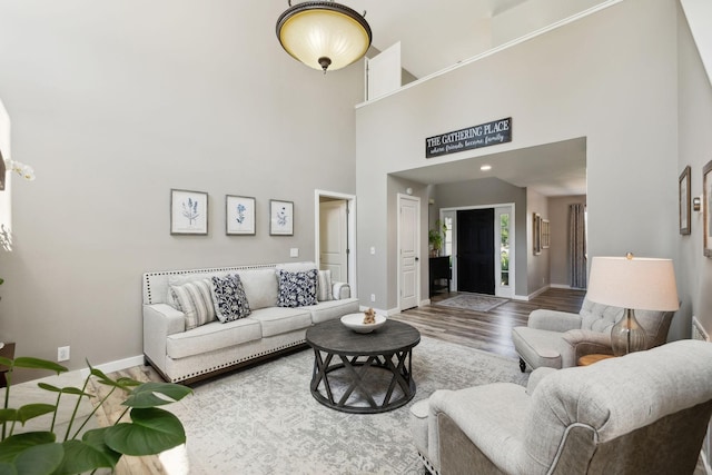 living room with baseboards, a high ceiling, and wood finished floors