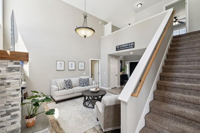 stairway featuring a ceiling fan, baseboards, wood finished floors, and a towering ceiling