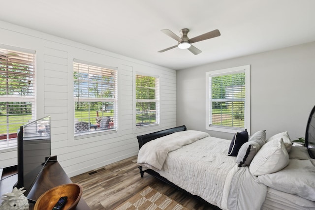 bedroom with a ceiling fan, wood finished floors, and visible vents