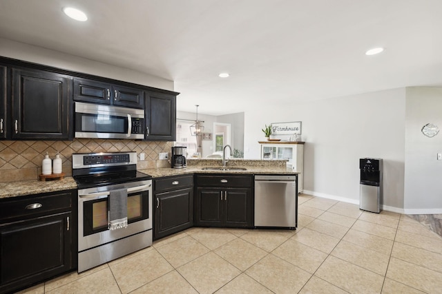kitchen featuring tasteful backsplash, a sink, baseboards, dark cabinetry, and stainless steel appliances