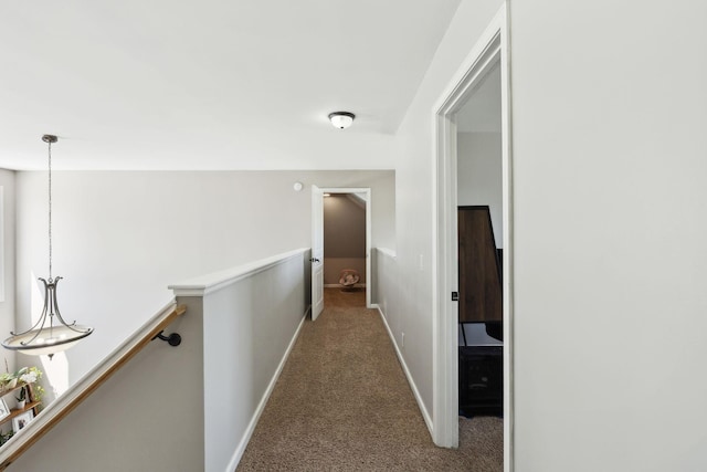 hallway with carpet floors, baseboards, and an upstairs landing