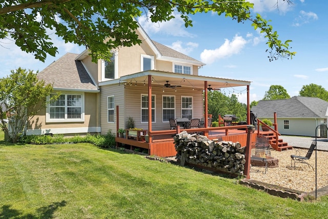 back of property with a lawn, ceiling fan, roof with shingles, and stucco siding