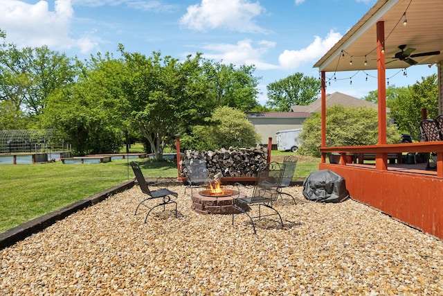 view of patio with ceiling fan, a fire pit, and a swimming pool