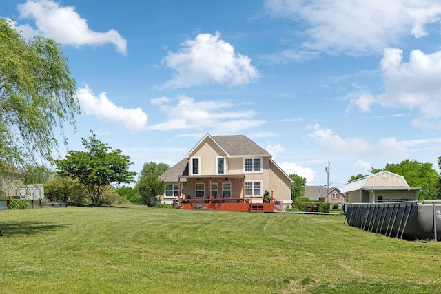 back of house with a lawn, stucco siding, and a deck