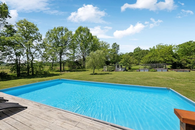 pool featuring a lawn, an outdoor structure, and a deck