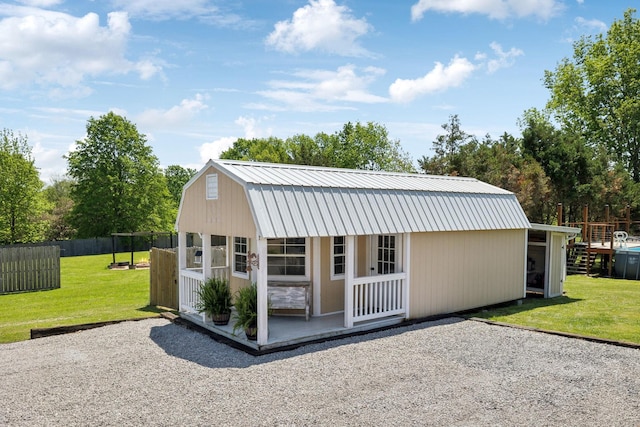 back of house with an outdoor structure, fence, a gambrel roof, metal roof, and a yard