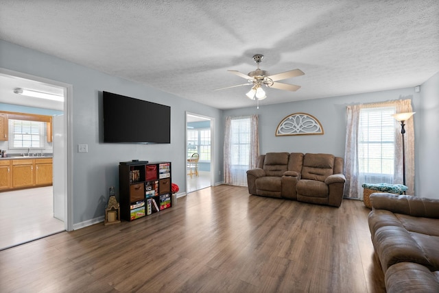 living room with light wood-type flooring, a textured ceiling, and a ceiling fan