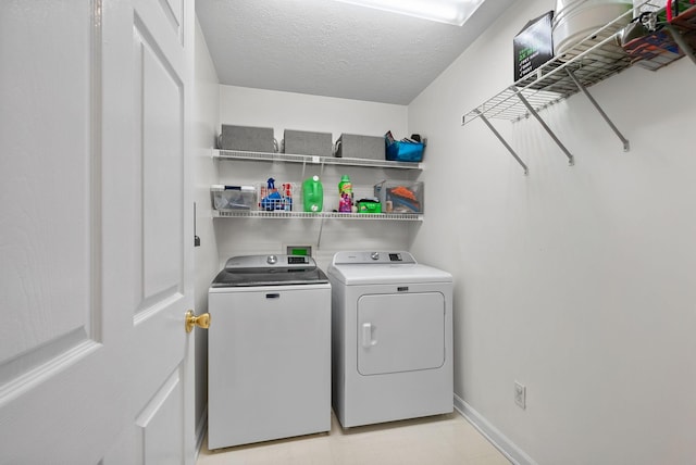 laundry area featuring a textured ceiling, washer and clothes dryer, baseboards, and laundry area