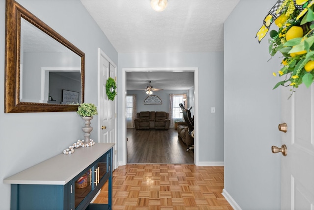 hallway with a textured ceiling and baseboards