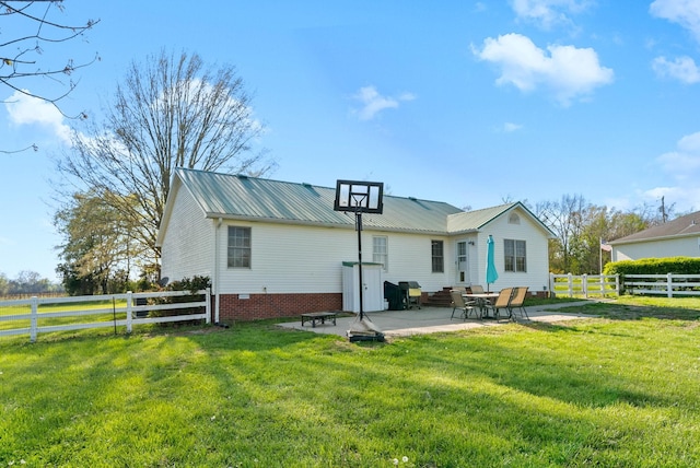 rear view of property with a yard, a patio area, a fenced backyard, and metal roof