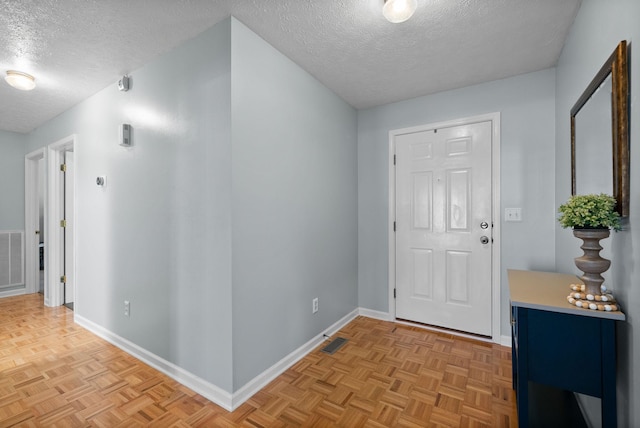entryway featuring a textured ceiling, baseboards, and visible vents