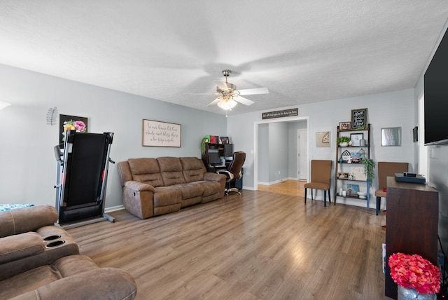 living area featuring a ceiling fan, baseboards, a textured ceiling, and light wood-style floors