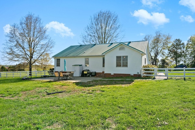 back of house featuring a fenced backyard, a patio area, metal roof, and a lawn