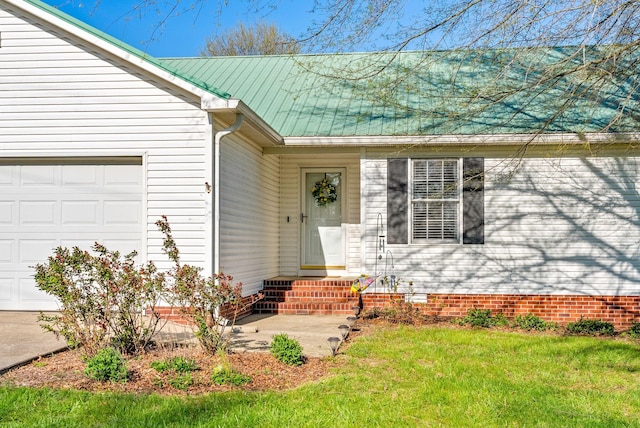 property entrance with a garage, a lawn, and metal roof