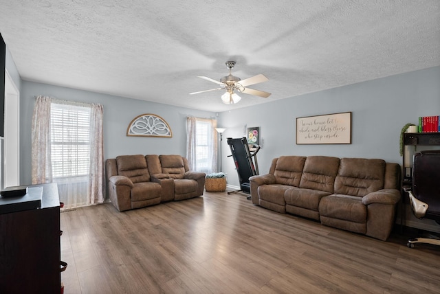 living area featuring a ceiling fan, wood finished floors, and a textured ceiling