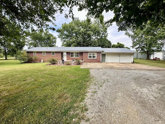 946 Monument Rd, Summertown, TN 38483 - ranch-style home featuring a front lawn, an attached garage, driveway, brick siding, and metal roof