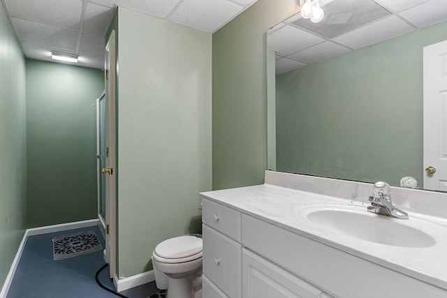 bathroom with vanity, a drop ceiling, baseboards, toilet, and an enclosed shower