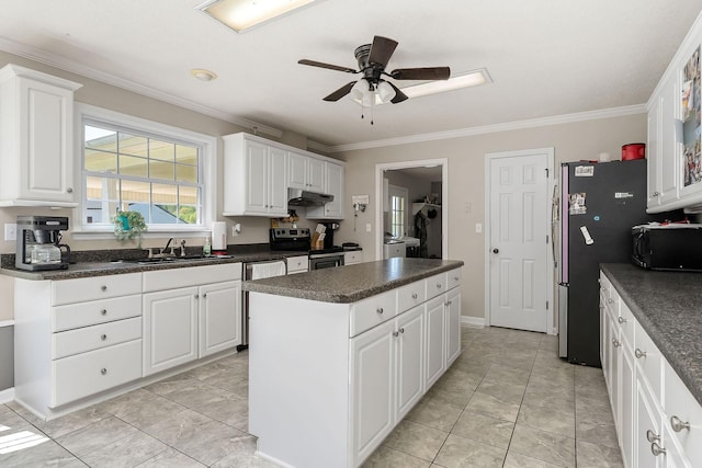 kitchen featuring dark countertops, a sink, appliances with stainless steel finishes, ornamental molding, and a kitchen island