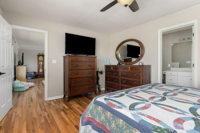 bedroom featuring baseboards, a ceiling fan, wood finished floors, and connected bathroom