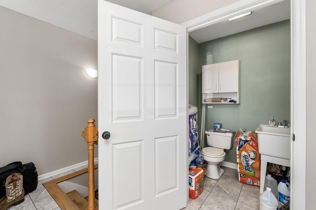 bathroom featuring baseboards, tile patterned flooring, and toilet