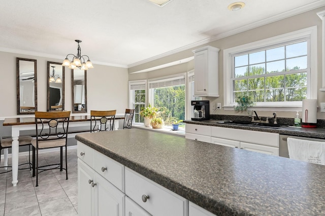 kitchen with ornamental molding, white cabinets, dark countertops, and a sink