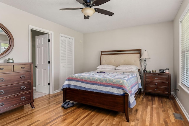 bedroom featuring a closet, light wood-style floors, ceiling fan, baseboards, and visible vents
