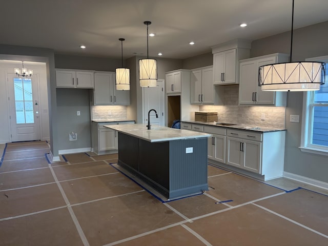 kitchen with decorative backsplash, a chandelier, a kitchen island with sink, a sink, and recessed lighting