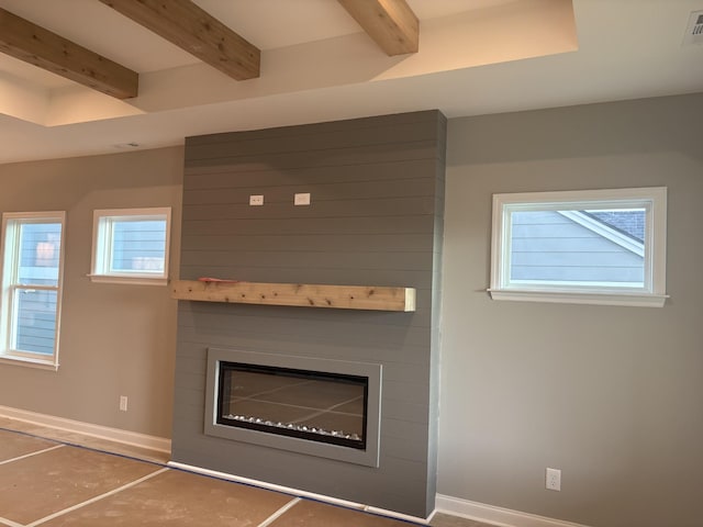 unfurnished living room with baseboards, a large fireplace, and beam ceiling