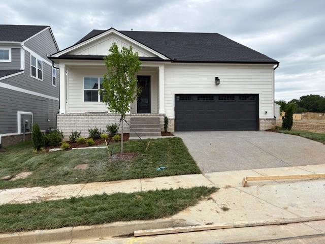 view of front of home with concrete driveway, an attached garage, brick siding, and a porch