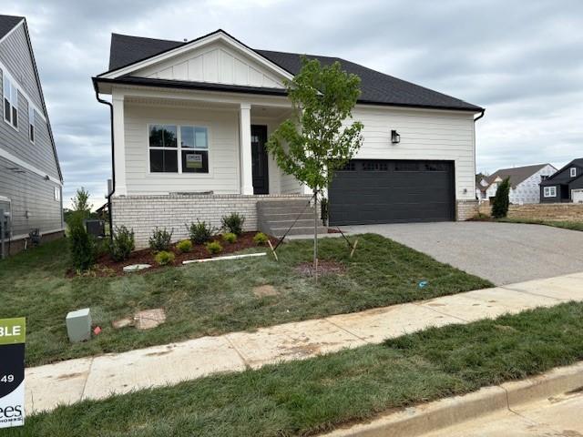view of front of property with concrete driveway, a porch, brick siding, and board and batten siding