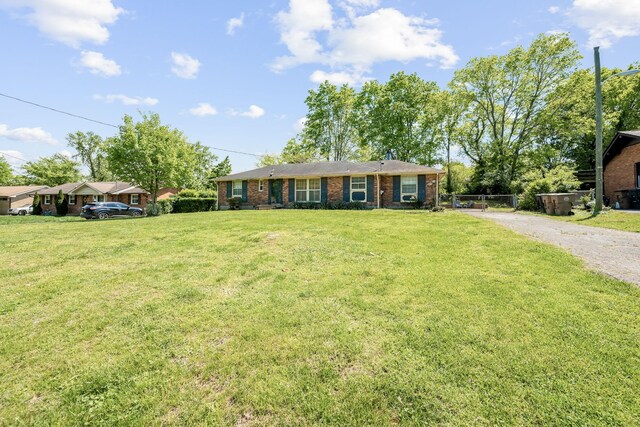 single story home featuring a front lawn, brick siding, and gravel driveway