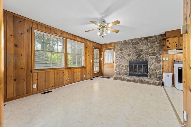 unfurnished living room featuring tile patterned floors, visible vents, a ceiling fan, wood walls, and a fireplace