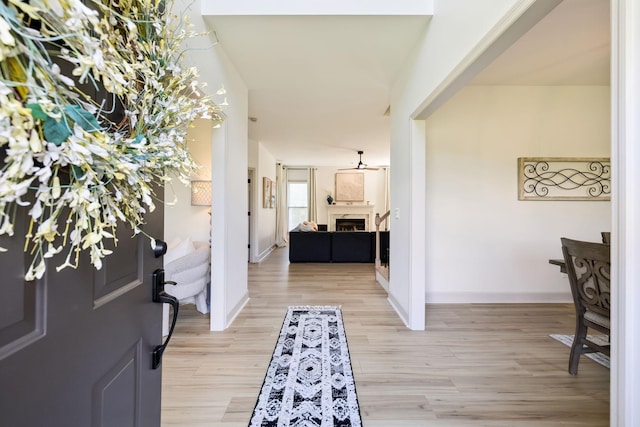 foyer with a fireplace, baseboards, and light wood-style floors