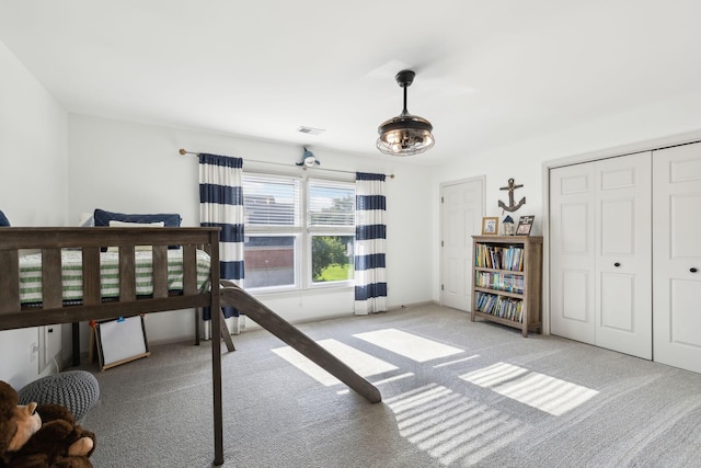 bedroom with light colored carpet, visible vents, and a closet