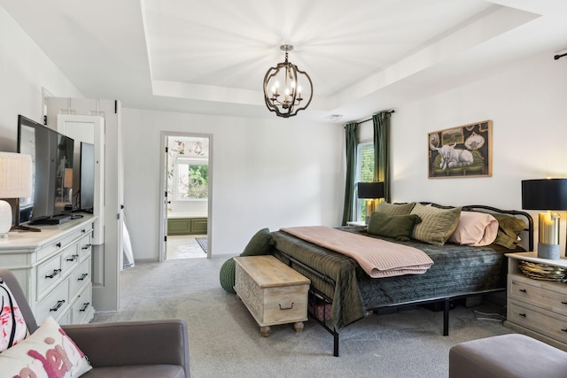 bedroom with carpet floors, an inviting chandelier, a raised ceiling, and connected bathroom