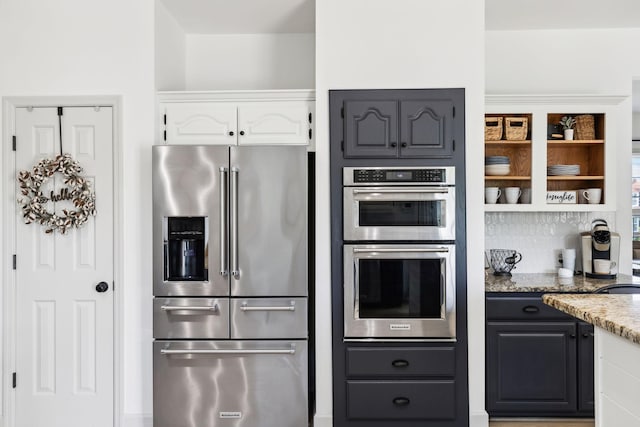 kitchen featuring stainless steel appliances, open shelves, light stone counters, and white cabinetry