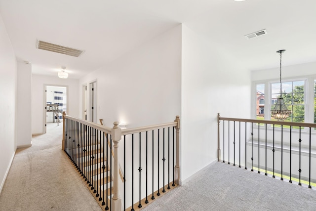 hallway with visible vents, carpet, and an upstairs landing