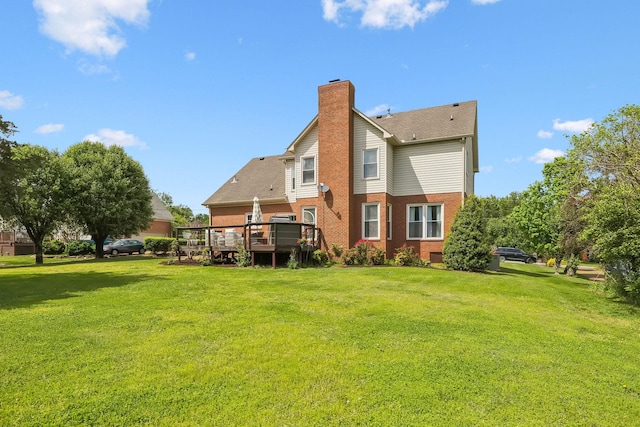 back of house with brick siding, a chimney, a yard, and a deck