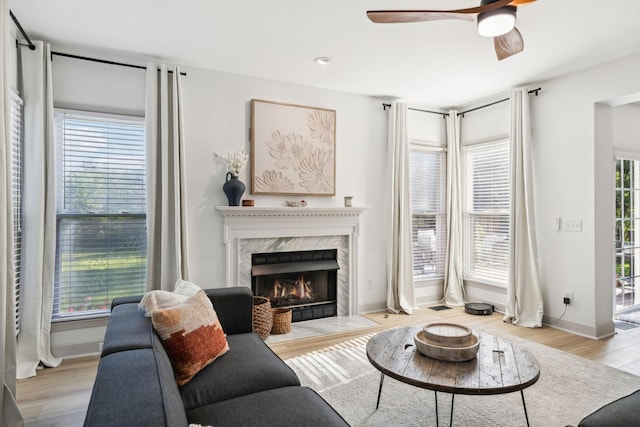 living area with a fireplace, baseboards, recessed lighting, a ceiling fan, and light wood finished floors