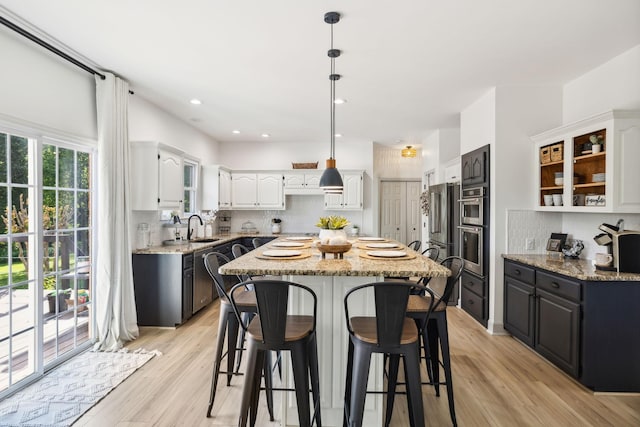 kitchen with white cabinets, a breakfast bar, a center island, and light wood-style floors