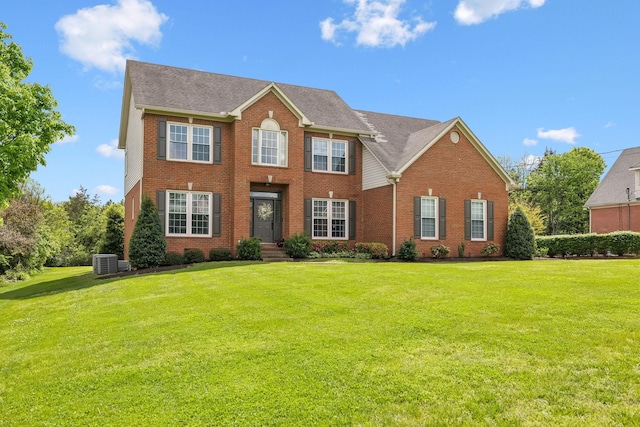 colonial inspired home featuring brick siding, central AC unit, and a front lawn