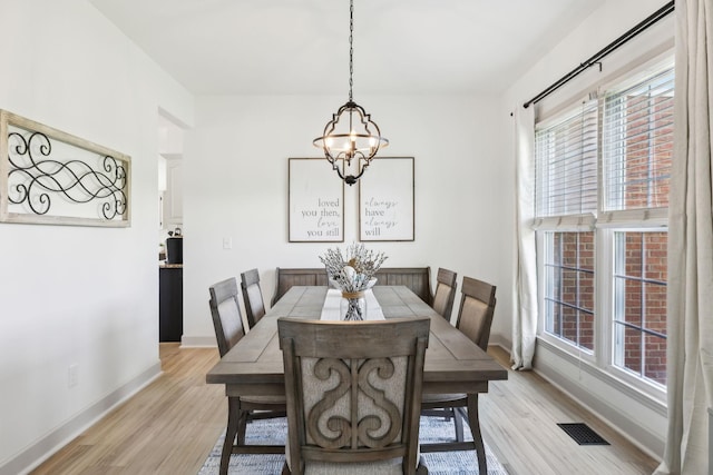 dining room with baseboards, light wood-style flooring, a chandelier, and visible vents