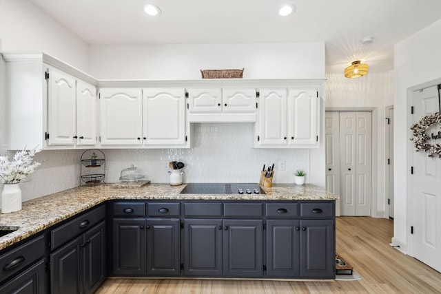 kitchen with white cabinets, backsplash, black electric stovetop, and light wood-style floors