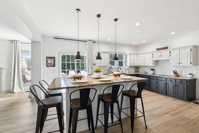 kitchen with light stone counters, a kitchen breakfast bar, a kitchen island, and white cabinets