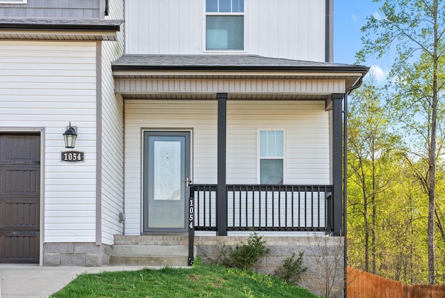view of exterior entry with a garage and covered porch