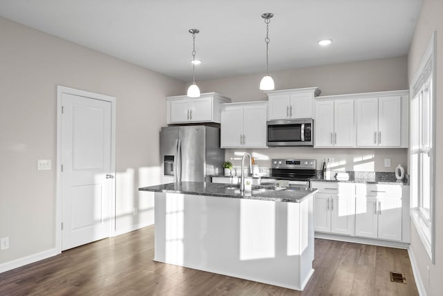 kitchen featuring visible vents, dark wood-type flooring, dark stone counters, appliances with stainless steel finishes, and white cabinetry
