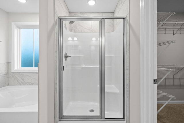 full bathroom featuring a walk in closet, a bath, and a shower stall