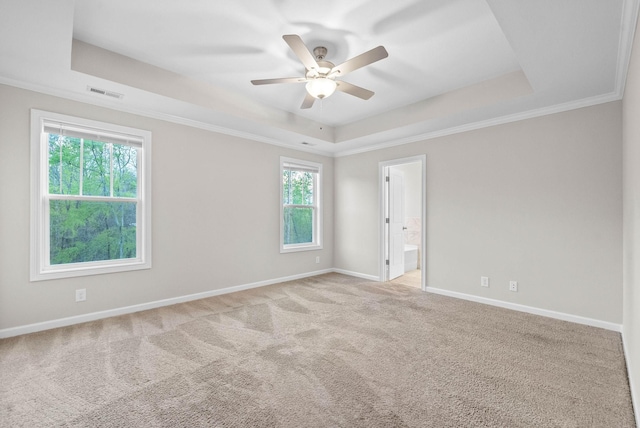 spare room featuring a raised ceiling, visible vents, baseboards, carpet flooring, and ceiling fan