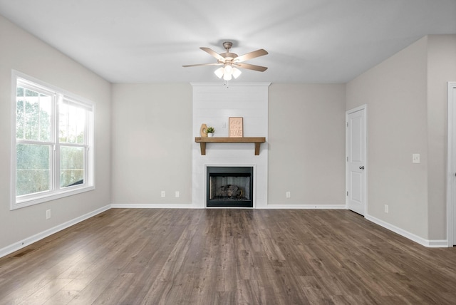 unfurnished living room featuring dark wood finished floors, baseboards, a ceiling fan, and a fireplace