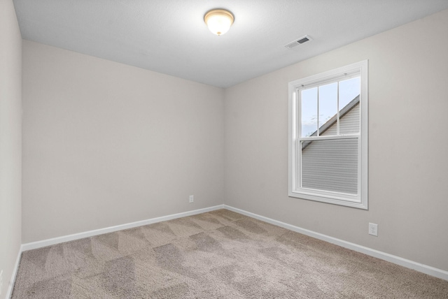 spare room featuring carpet floors, visible vents, and baseboards